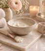 Cream facial mask in a ceramic bowl with brush and towels