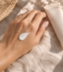 Sunscreen on the back of a hand beside a sunscreen tube
