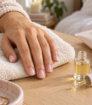 Manicured hand beside cuticle oil, hand cream and a nail file on a soft towel